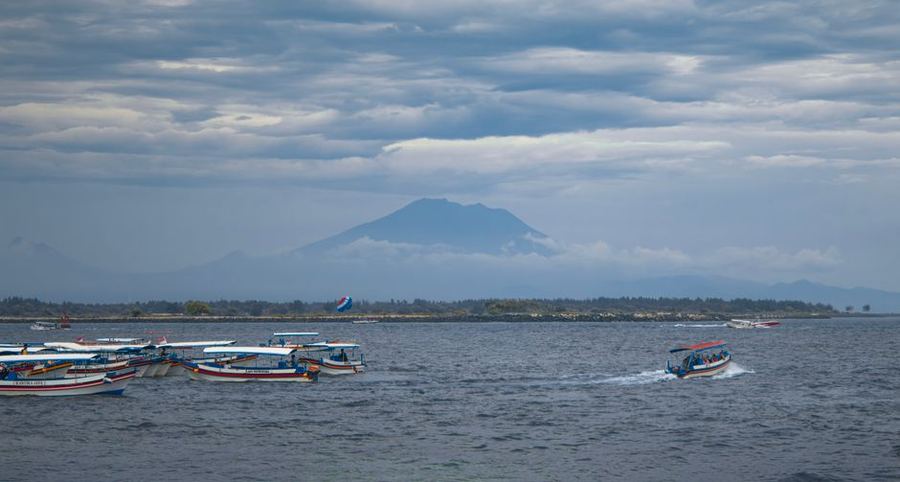 Boats on a calm sea with a mountain behind